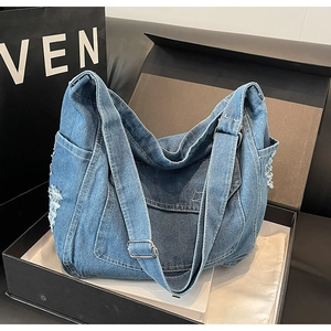Vista dettagliata della borsa in denim con trama usurata e tasca laterale nel box display
