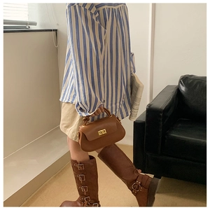 Brown leather crossbody bag detail on model with blue striped shirt and buckled boots