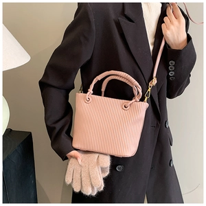 Close-up of pink pleated bucket bag with rolled handles and gold metal hardware