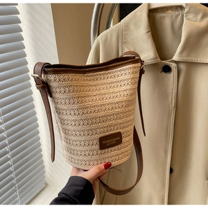 Close-up of woven straw bucket bag with leather trim and adjustable shoulder strap detail