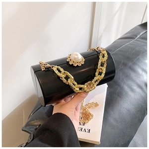 Detail of black acrylic cylinder bag with pearl clasp and heavy gold chain strap