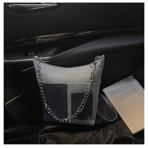 Detail of denim patchwork bucket bag with silver chain and leather straps in a car
