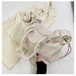 Detail shot of a cream PU leather tote bag featuring a unique pleated cloud handle design