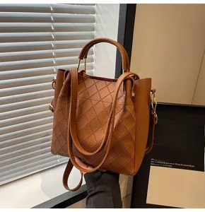 Detail of caramel brown quilted leather bucket bag with top handle and crossbody strap