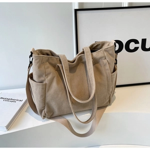 Detail of beige corduroy tote bag showing textured fabric, side pocket and strap hooks