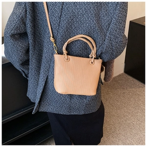 Close-up of vertical pleated texture and gold hardware on caramel bucket bag