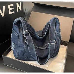 Dettaglio della borsa a tracolla in denim blu con bordi sfrangiati e hardware argento