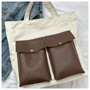 Detail of canvas tote bag featuring brown leather pockets and silver metal snap buttons