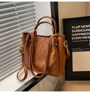 Detail view of brown leather bucket bag showing diamond stitching and metal hardware