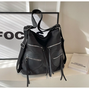 Detail of black corduroy backpack featuring heart-shaped zipper pockets and silver hardware