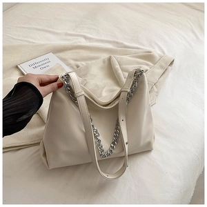 Detail of off-white soft leather tote bag with silver chain decoration on knit background