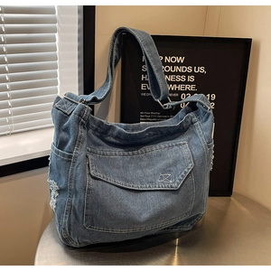 Dettaglio della trama denim con cuciture bianche e fibbia in metallo regolabile della borsa