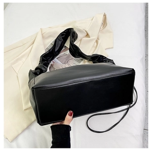 Detail of black baguette bag featuring pleated shoulder strap and smooth PU leather finish