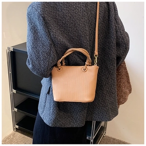 Detailed texture of camel pleated bucket bag with woven ring handle and shoulder strap