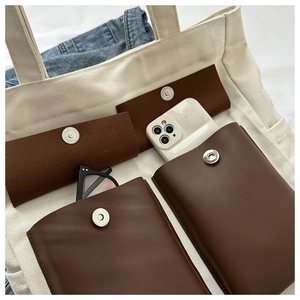 Detail of four brown multi-textured pockets on white canvas tote bag with magnetic buckles