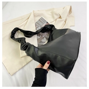 Close-up of black glossy PU leather shoulder bag with stylish knotted pleat strap detail