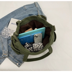 Detail view of green corduroy tote bag showing interior compartment and large capacity