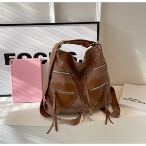 Detail view of coffee corduroy backpack featuring heart-shaped leather pockets and silver zippers
