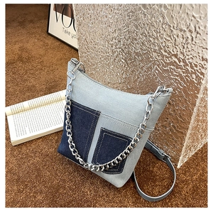 Detail of light blue denim bucket bag with silver chains and adjustable leather strap