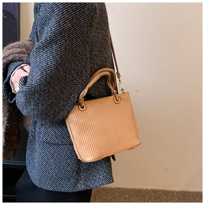 Macro shot of a light brown pleated leather bucket bag with golden metal hooks and hardware