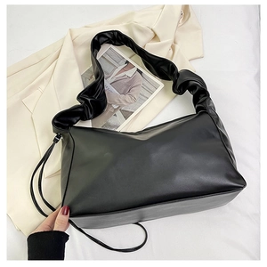 Detail of black pleated shoulder bag with soft faux leather texture and drawstring side