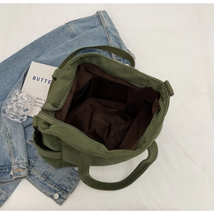 Detail of dark green corduroy tote bag showing interior lining, pocket, and zipper closure
