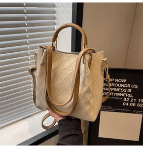 Detail of cream bucket bag showing lychee grain leather texture and diamond lattice stitching