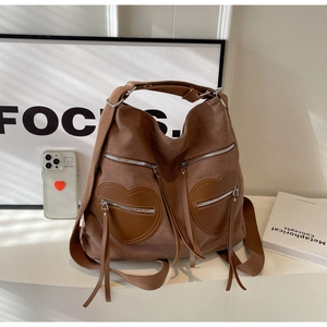 Close-up of vintage brown canvas backpack with double heart pockets and long tassels
