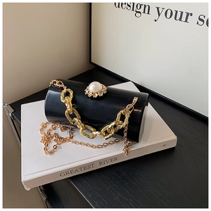 Detail of black cylindrical acrylic evening bag with oversized pearl clasp and gold chain