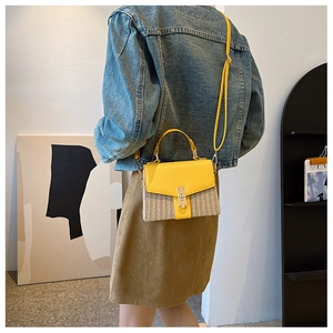 Detailaufnahme der Strohtextur und des goldenen Metallverschlusses an der gelben Ledertasche