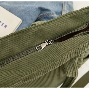 Close-up of the metal zipper closure and ribbed corduroy texture on dark green tote bag
