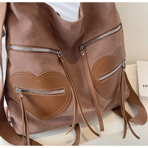 Detailed view of brown corduroy backpack with dual heart-shaped zipper pockets and wide straps