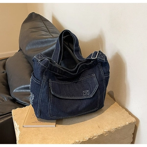 Dettaglio della borsa tote in denim blu con cuciture bianche a contrasto e finitura vintage