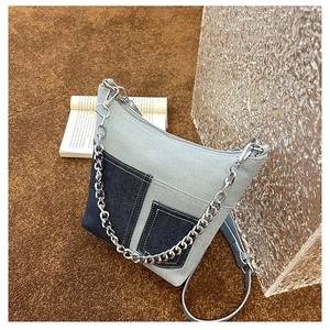 Detail of patchwork denim crossbody bag with silver chain and dual blue tone textures