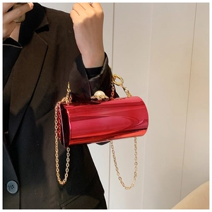 Red acrylic cylinder evening bag with large pearl clasp held by a model in black blazer