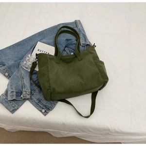 Green corduroy tote bag showing side pocket detail and texture on denim jacket