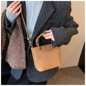 Vertical pleated texture bucket bag detail showing brown faux leather and woven handle