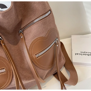 Detail of vintage canvas backpack featuring heart leather patch and tassel zipper