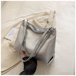 Detail of silver metallic tote bag showing textured leather and chunky chain strap