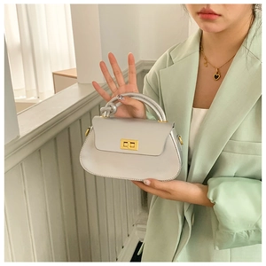 Detail of silver metallic handbag featuring a knotted handle and golden twist lock closure