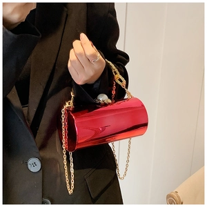 Detail of red cylindrical evening bag with gold chain strap and large pearl clasp lock