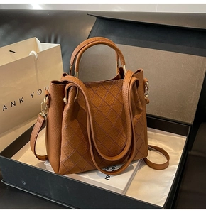 Detailed view of brown lychee grain leather bucket bag with elegant diamond stitching