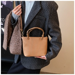 Detail of caramel brown pleated bucket bag showing vertical pleats and woven handles