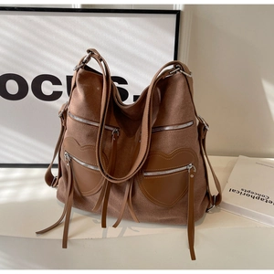 Detailed close-up of brown corduroy backpack featuring heart-shaped leather pockets and tassels