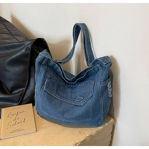 Dettaglio della borsa a tracolla in denim blu con cuciture a contrasto e frange