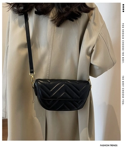 Detail of black quilted shoulder bag with V-shaped stitching and golden metal hooks