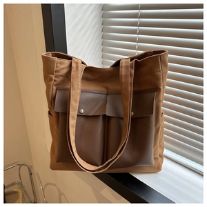 Detail of canvas tote bag with brown faux leather pockets and silver metal snap buttons