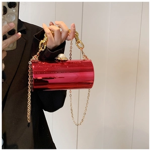 Detail of red cylindrical clutch bag with pearl clasp and gold chain straps
