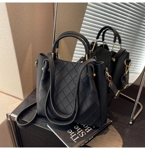 Detail view of the black quilted leather texture and golden hardware on the handbag