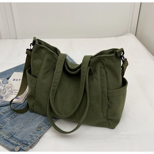 Detail view of dark green corduroy tote bag featuring adjustable strap and side pocket